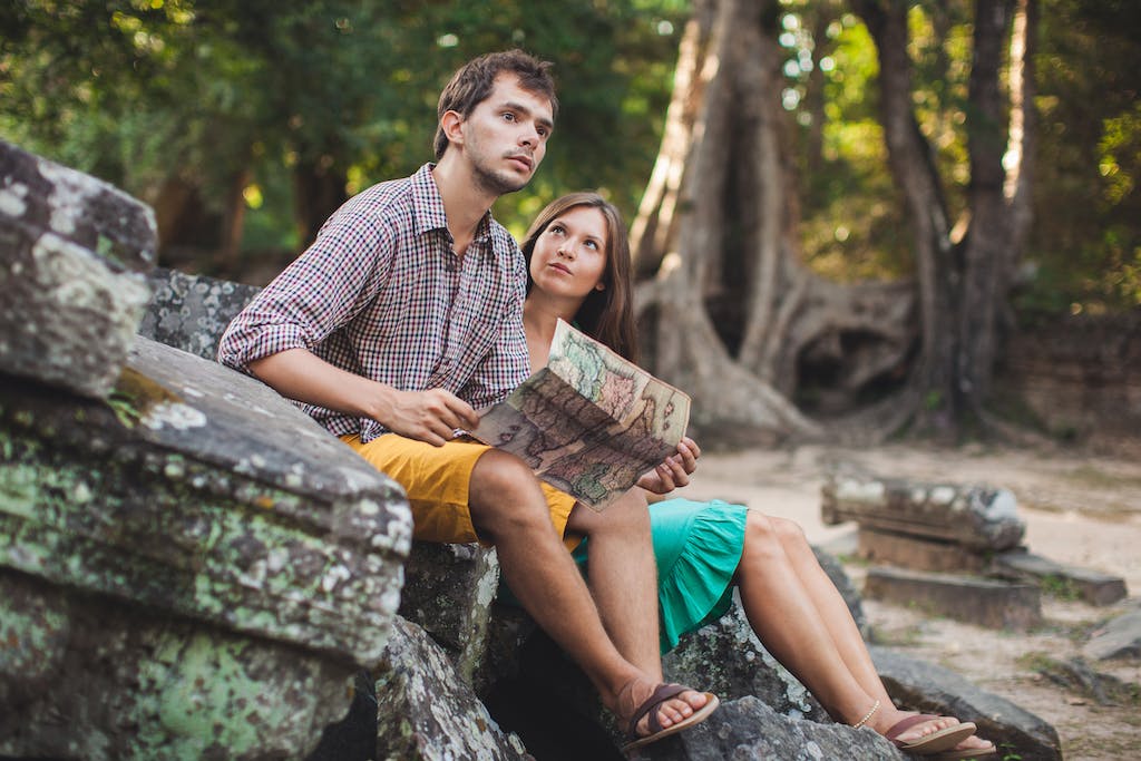 A Couple Sitting on a Rock Holding a Map